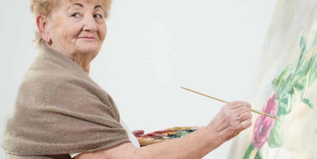 Elderly Woman Holding Paintbrush and Smiling in Independent Living Facility