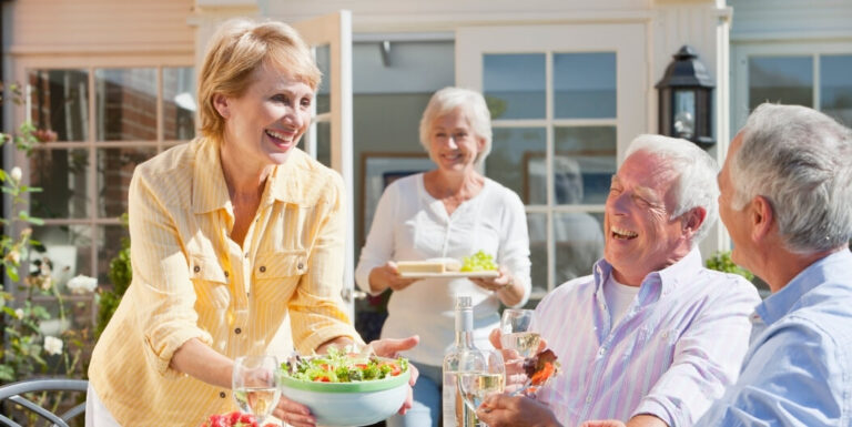 Elderly Woman Serving Salad to Friends at an Outdoor Gathering at Independent Living Facility