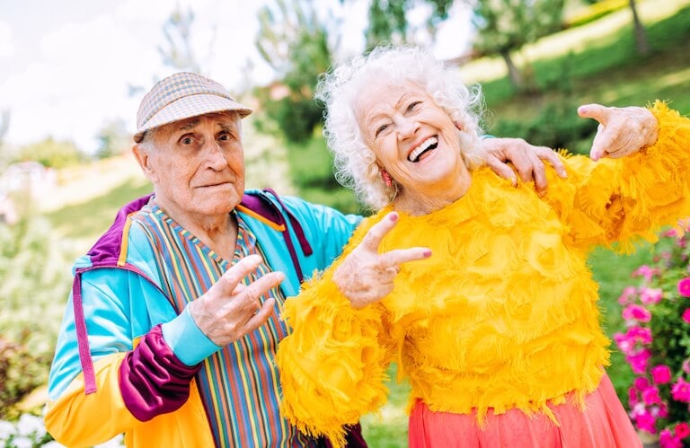 Colorfully Dressed Elderly Couple Posing Playfully in the Garden in Independent Living