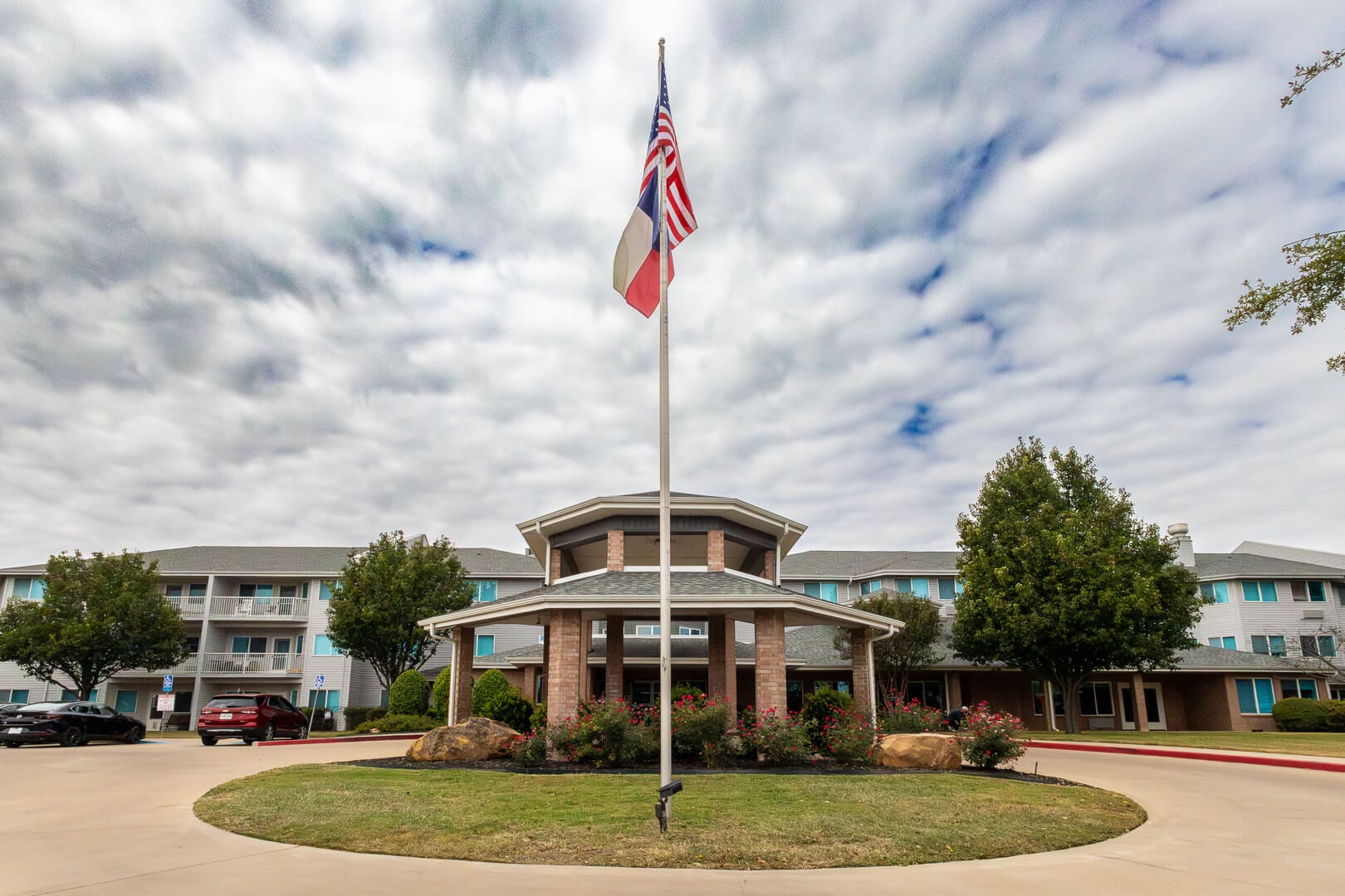 Front Exterior With American and Texas Flags Flying at an Independent Living Community