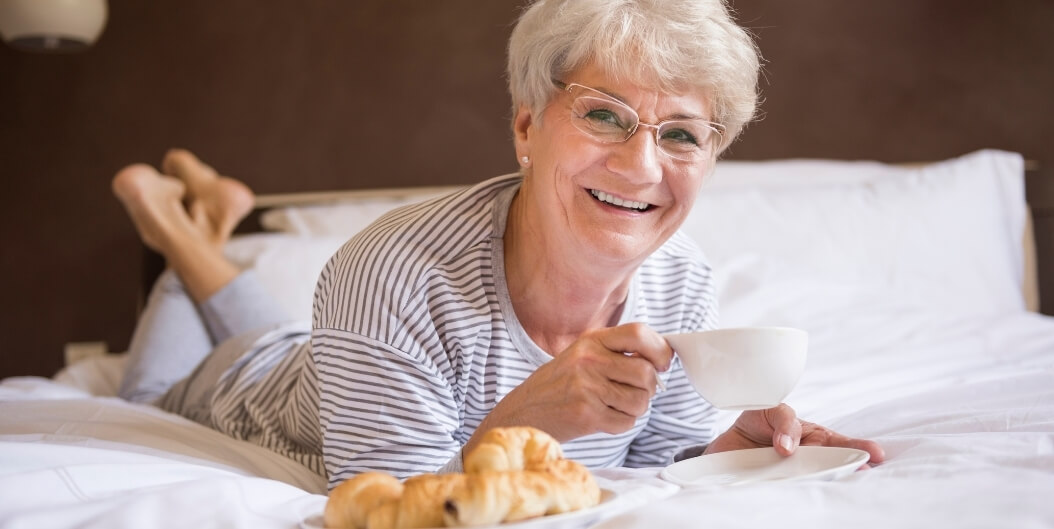 Elderly Woman Enjoying Breakfast in Bed at Independent Living Facility